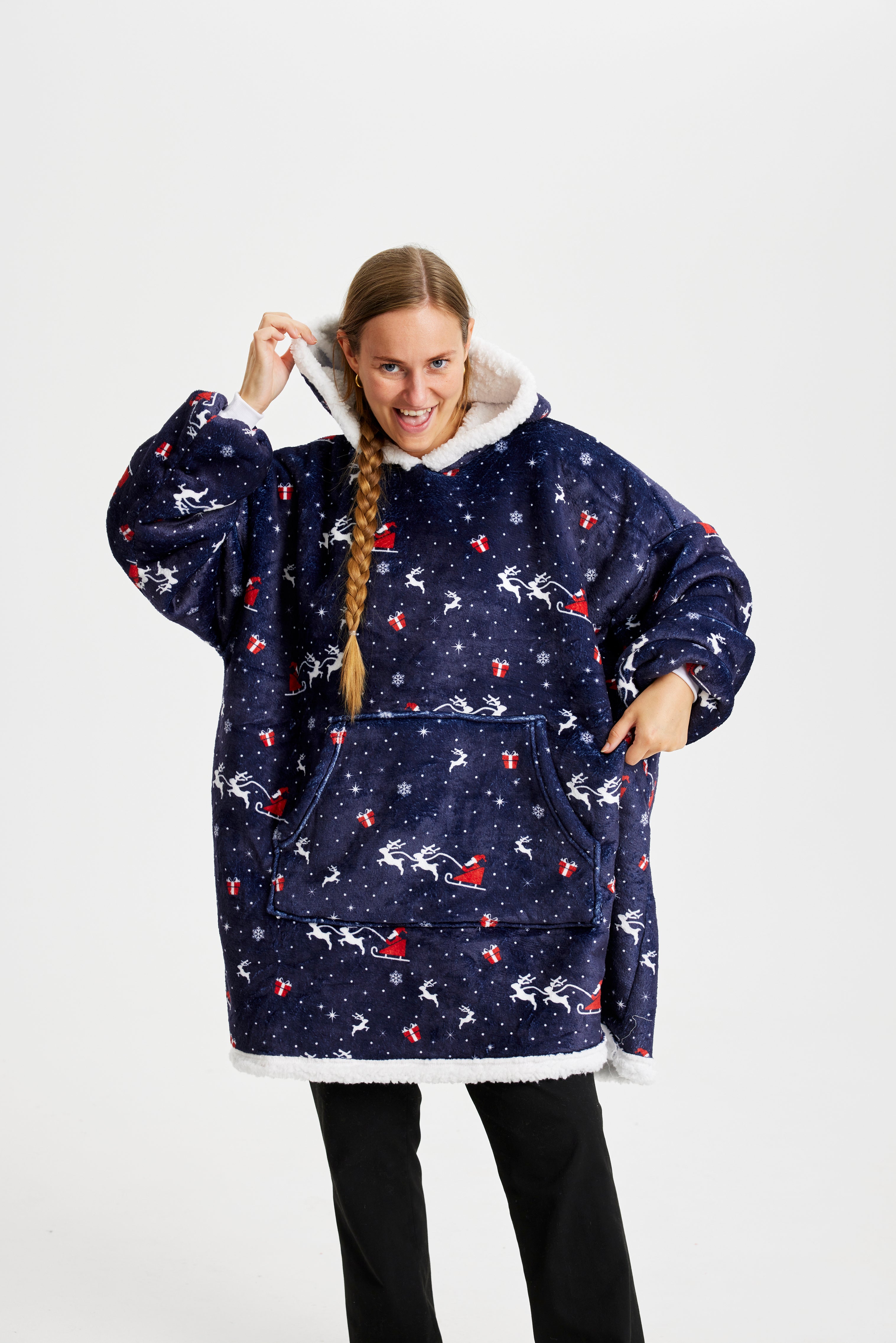 Eine posierende Frau, die einen blauen gemusterten Weihnachts-Kapuzenpullover trägt.